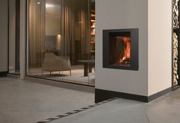 Insert à bois avec vitre coulissante escamotable. Cet appareil intégré peut être utilisé comme un foyer fermé ou comme un feu ouvert en relevant la vitre.